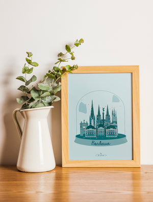 Carte postale illustrée intitulée “Bordeaux en Hiver" par Julie Roubergue, représentant les monuments emblématiques de Bordeaux dans une boule de neige.