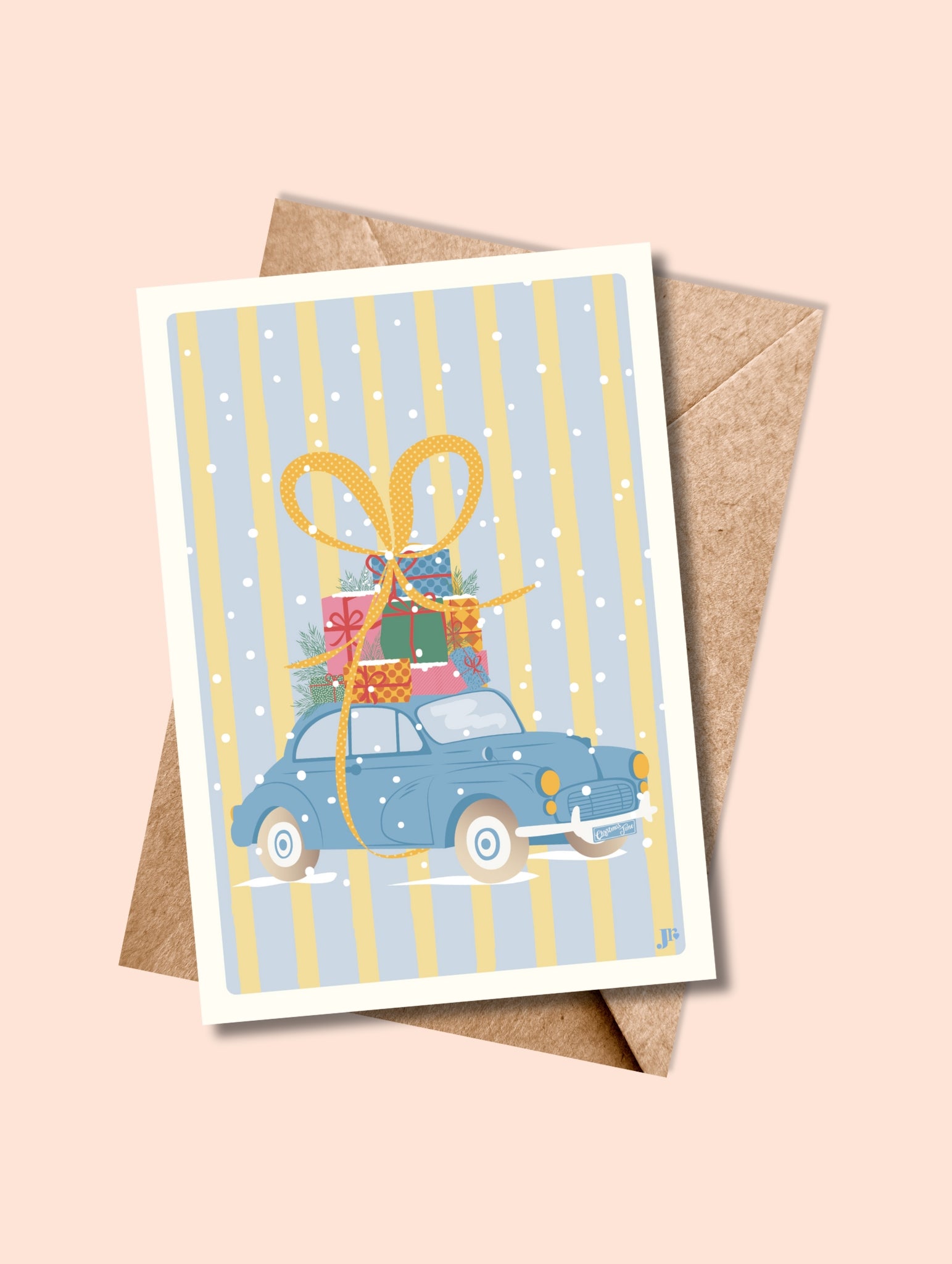 Carte postale En route pour Noël avec enveloppe kraft, voiture bleue vintage et cadeaux colorés sous la neige.